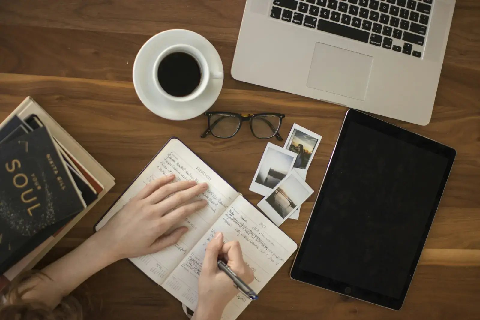 An author writing in a notebook at a desk